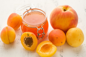homemade jam of ripe peaches on a white wooden background