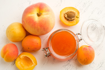 homemade jam of ripe peaches on a white wooden background