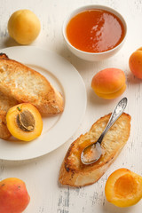 homemade jam of ripe peaches on a white wooden background