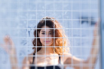 Young woman behind the metal mesh