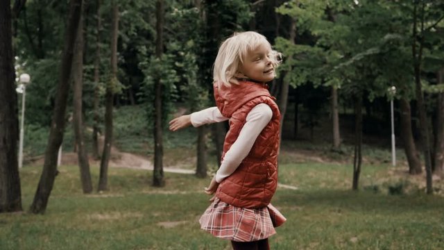The little cheerful blond girl laughing and throwing a piece of a plastic shaped like a plate as a game. Slow motion. HD