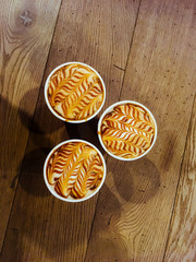 Top view of latte art coffee take away paper cup on wooden background