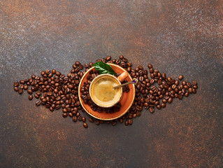 Coffee beans with cup of cofee on brown concrete table with copy space for design.