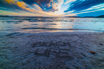 Beach life written on the sand at sunset