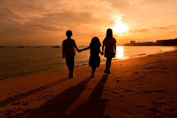 Silhouette of little kid girls enjoy on the beach with sea and sunset background