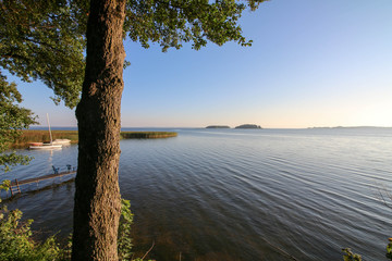 A scenic early morning panorama of the Sniardwy lake with Wyspa Pajecza and Czarci Ostrow islands visible in the background.