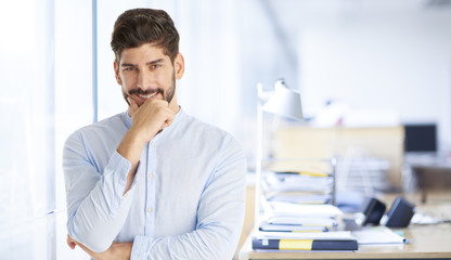 Thinking young businessman portrait. Shot of a young man standing with hand on chin and looking thoughtfully.