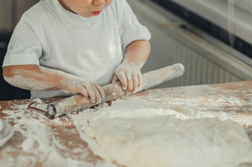 A child with a rolling pin at the table