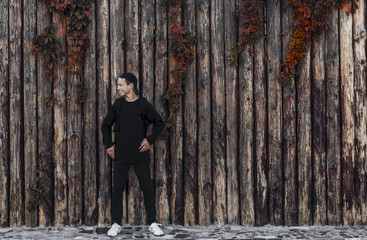 Fototapeta na wymiar Handsome young man Standing near a wooden wall