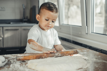Fototapeta premium A child with a rolling pin at the table