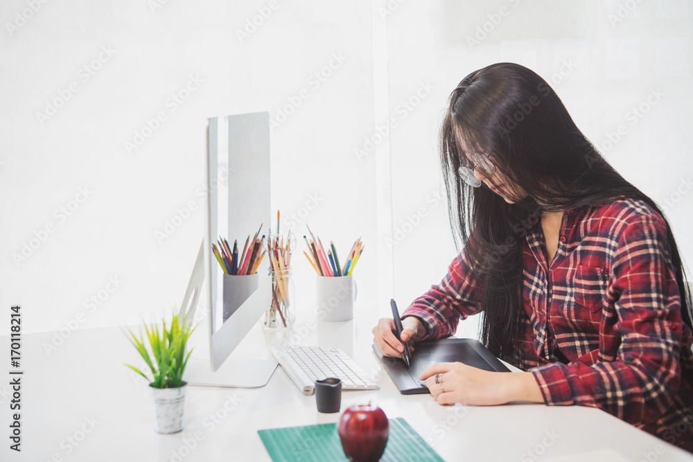 Aufkleber female graphic designer working on computer while using graphic tablet at desk in the office