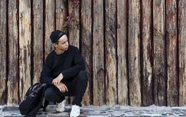 Handsome young man sitting near a wooden wall