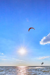 Man riding a kite surfing on the waves in the summer.