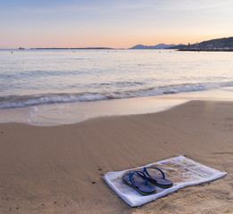 Flip flops on a sandy beach at sunset