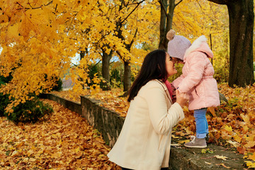 Mother walks with a child in the park in the autumn fall.