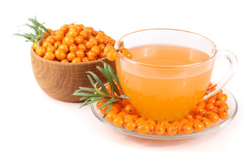 Sea buckthorn tea in a glass and wooden bowl with berries isolated on white background