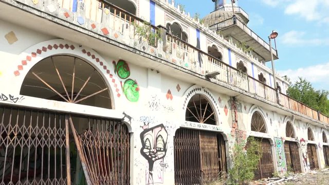 Abandoned Arabian building with murals and minaret in Consonno, Italy. Arabic style construction with graffiti and wild vegetation, desolate and scary place, ghost town