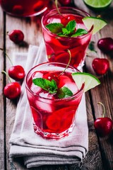ice refreshing cherry sangria in glass with ice cubes, lime and mint