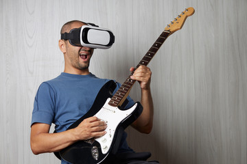young adult playing guitar at home using viewer for augmented reality
