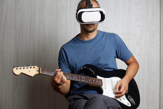 young adult playing guitar at home using viewer for augmented reality