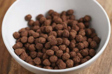 chocolate cereal balls in white bowl for breakfast on wooden table