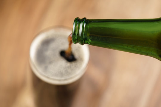 Dark Beer Pouring In Glass On Wood Table From Above