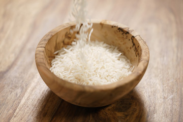 dry basmati rice fall in wood bowl on table