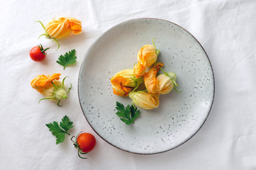 Zucchini (courgette) flowers on plate. Healthy summer food. Top view. Fresh vegetables decoration.