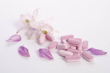 Obraz na płótnie Canvas Alternative medicine tablets with flowers and petals on table