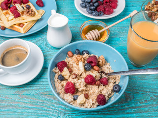 Bowl of oatmeal with raspberries and blueberries on a blue wooden table.