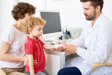 Portrait of  curly little kid with injured arm at doctors office