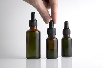 Isolated hand holding a medical brown drop bottle over a white b