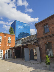yard in Lodz city center with skyscraper and old red brick factory with blue sky backgrounds
