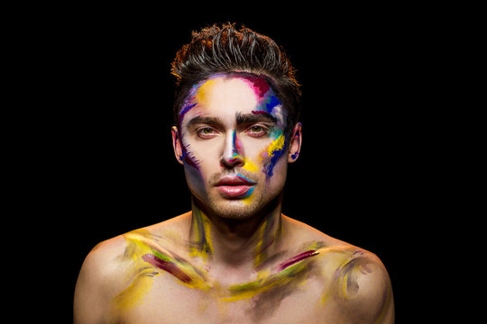 Handsome guy, makeup art. Young man on black background. The living palette.
