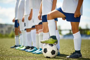 Low section portrait of junior football team : legs of boys standing in row with captain stepping...