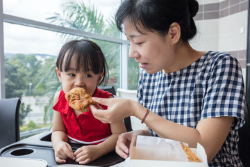 Asian Chinese mother and daughter eating fried chicken