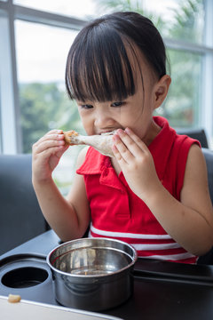 Asian Chinese little girl eating fried chicken