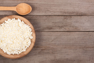 Cottage cheese in a wooden bowl on old wooden background with copy space for your text. Top view