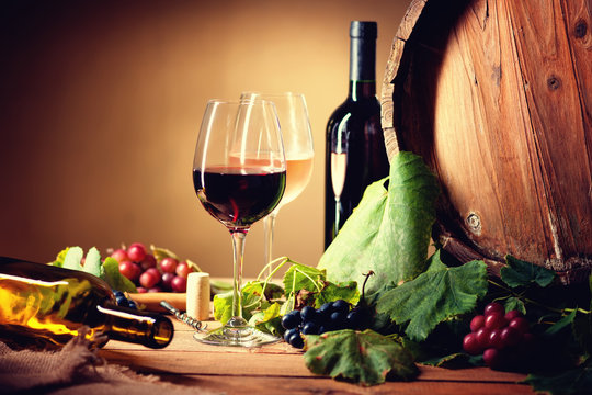 Wine bottles, glasses, grapes and barrel 