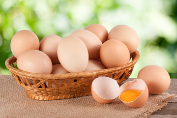 eggs in a wicker basket on a wooden board with blurred garden background