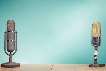 Old retro big microphones from 50s on table front gradient mint green background. Vintage style filtered photo