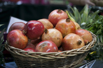 the Ripe pomegranates in a wicker basket on the counter in the market for sale.