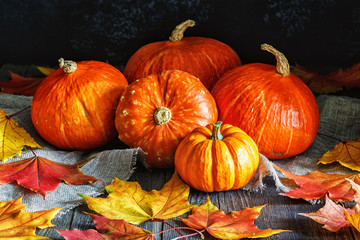 Autumn pumpkin with maple leaves on wooden background.
