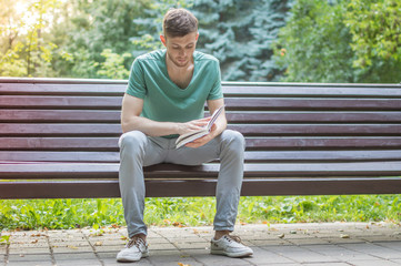 Obraz premium Young man reading book in the park