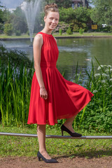 junges, hübsches Mädchen im Sommer mit Hochsteckfrisur und rotem Sommerkleid beim Fotoshooting...
