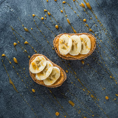 Toast with peanut butter, banana and caramel. Vegetarian natural breakfast. Flat lay, top viewii