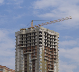 Building crane and building under construction against clear blue sky