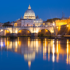Fototapeta na wymiar Saint Angel bridge and Saint Peter Cathedral with a mirror reflection in the Tiber River during morning blue hour in Rome, Italy.