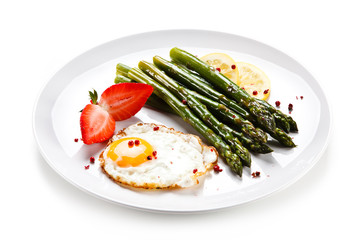 Fried egg with asparagus on white background 