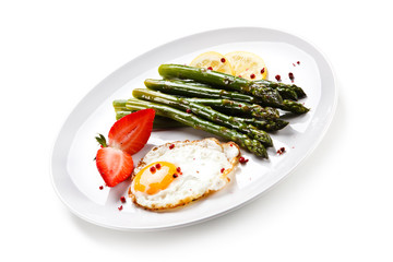 Fried egg with asparagus on white background 